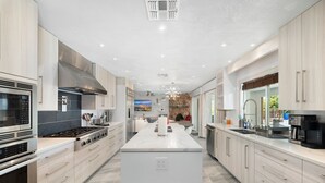 A modern kitchen with a central island, stainless steel appliances, and light wood cabinetry. - Luxury 4 Bed/4Bath! Private Pool & Mountain Views! (Phoenix)