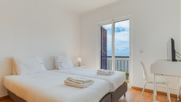 A bedroom with two beds, a desk, and a chair.