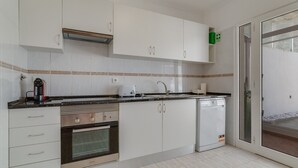 A modern kitchen with white cabinets, a built-in oven, a dishwasher, and a coffee maker.