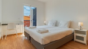 A bedroom with a bed, bedside tables, a desk, and a chair.