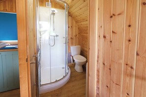 A wooden cabin bathroom with a shower, toilet, and a wooden floor. - Ocean View 6 - 1 Bed Pod - Llanrhidian (Swansea)