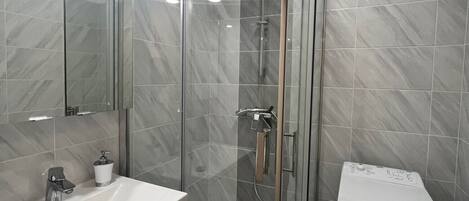 Une salle de bain moderne avec une douche à parois de verre, un lavabo blanc et des toilettes.