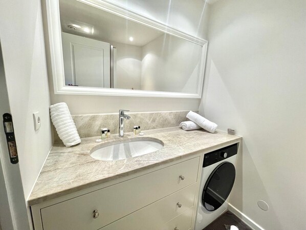 A bathroom with a sink, mirror, towel, and a washing machine. - Marina 3 bedrooms (Cannes)