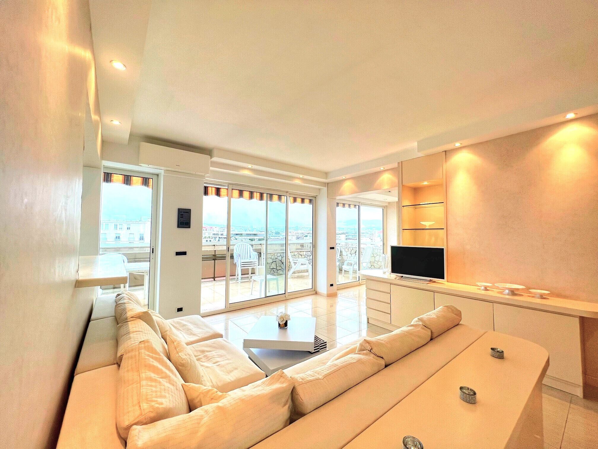 Een moderne woonkamer met een bank, een televisie en een balkon met uitzicht.