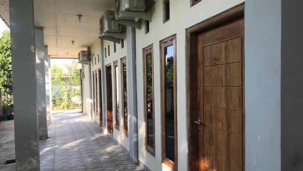 A corridor with tiled flooring, wooden doors, and air conditioning units.