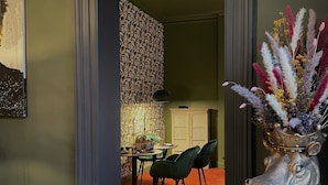A dining area with a round table, green chairs, and a patterned wallpaper. - Maison Héronnière (Compiègne)