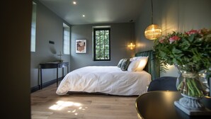 A bedroom with a large bed, a window, a bedside table, and a hanging light fixture. - Maison Héronnière (Compiègne)
