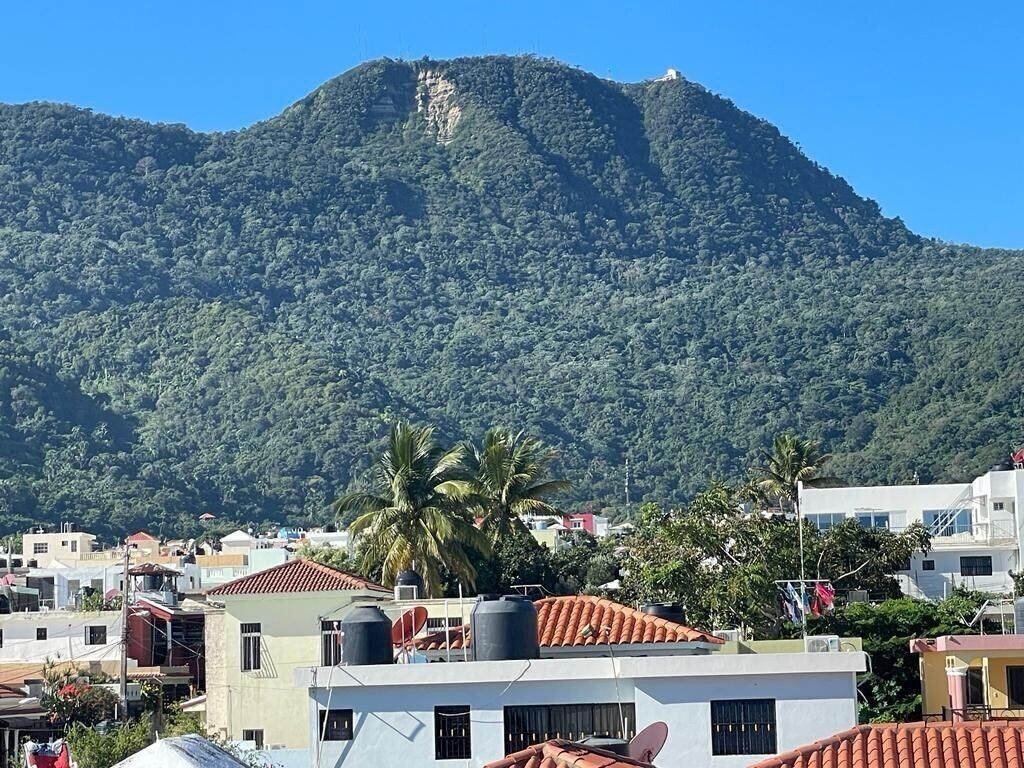 Un quartier résidentiel avec des maisons, une montagne en arrière-plan et un ciel dégagé.
