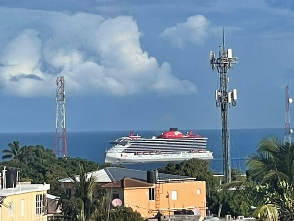 Um cruzeiro no oceano, com céu claro e uma torre de comunicação ao fundo.