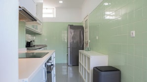 A compact kitchen with a stainless steel refrigerator, a built-in oven, and a microwave.