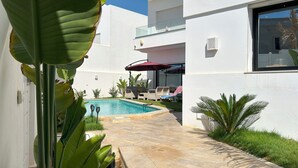 A modern house with a swimming pool, outdoor seating, and lush greenery. - Villa a Hammamet Centre, 300 Metre du Theatre, Piscine, Climatisée, 4 Chambre (Hammamet)