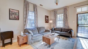 A living room with two sofas, a coffee table, and a lamp. There are curtains on the windows and a poster on the wall. - Cooper Young Vibes Su (Memphis)