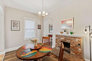 A dining area with a brick fireplace, wooden dining table, and chairs. - Bungalow ON Overton Square (Memphis)
