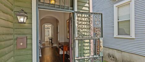 A wooden interior with a staircase leading to an upper level, a small table, and a door with decorative metalwork.