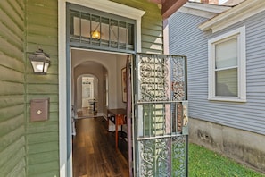 A wooden interior with a staircase leading to an upper level, a small table, and a door with decorative metalwork. - Bungalow ON Overton Square (Memphis)