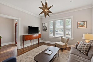 A living room with a star-shaped light fixture, a television on a wooden stand, a sofa, and a patterned rug.