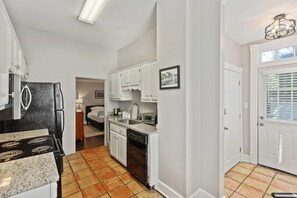 A compact kitchen with white cabinets, a black refrigerator, and a dishwasher.
