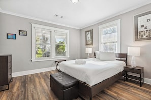 Een slaapkamer met een groot bed, twee nachtkastjes, een bankje en een dressoir.