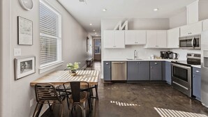 A modern kitchen with white cabinets, a stainless steel dishwasher, and a built-in oven.
