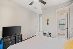 Relax in this serene bedroom with a large bed, flat-screen TV, and ceiling fan.