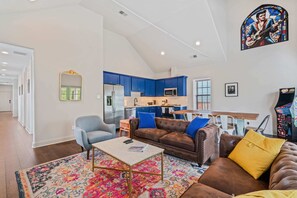 Relax in this stylish living space with a high ceiling, featuring a comfortable sofa, armchair, and coffee table.