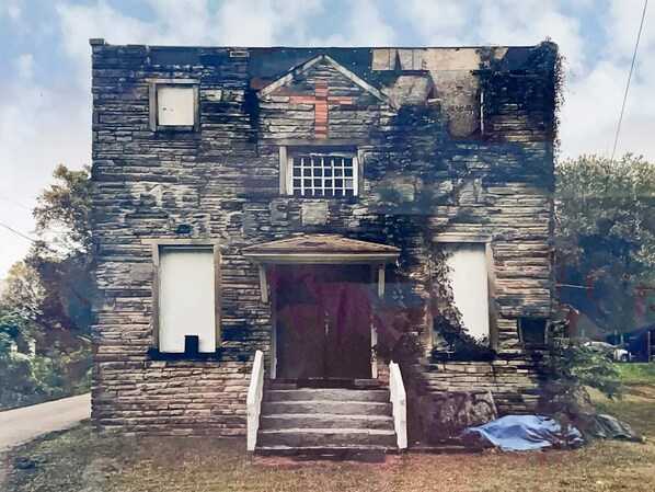 Stunning stone building with a central entrance and symmetrical facade, featuring a staircase and two side windows.