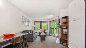 A modern living room with a dining area, a sofa, a coffee table, and a bookshelf.