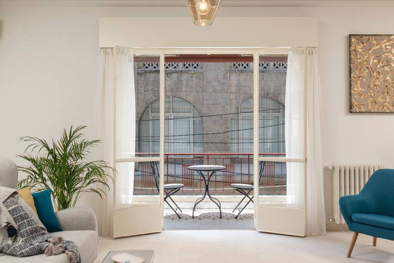 A living room with a large glass door leading to a balcony with a table and chairs.