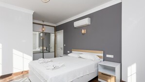 A modern bedroom with a large bed, a bedside table, a mirror, and an air conditioning unit on the wall. - Villa Capital - Five Bedroom Villa, Sleeps 10 (Dalyan)