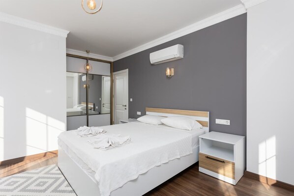 A modern bedroom with a large bed, a bedside table, a mirror, and an air conditioning unit on the wall. - Villa Capital - Five Bedroom Villa, Sleeps 10 (Dalyan)