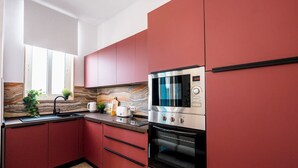 Een moderne keuken met rode kastjes, een roestvrijstalen magnetron en een inbouwoven.