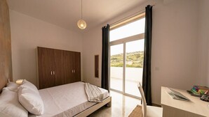 Een slaapkamer met een bed, een bureau en uitzicht op de omgeving.