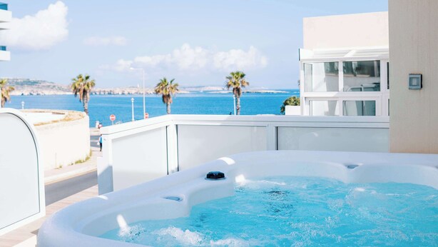 A hot tub with a view of the sea and palm trees. - Stunning 4BR Villa w/ Heated Jacuzzi in St. Paul's (San Pawl il-Bahar)