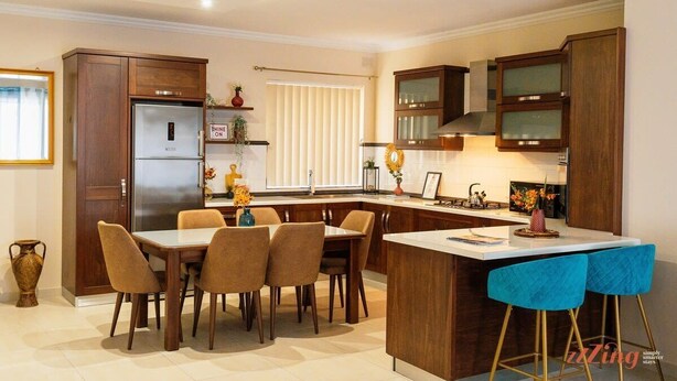 A modern kitchen with a central island, wooden cabinets, and a dining area with chairs. - A pretty holiday home in Malta’s fishing village (Marsaxlokk)