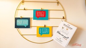 A wall-mounted rack with three speech bubble-shaped cards displaying 'BONGU', 'MHUX HEKK', and 'U EJJA!' in different colors. - A pretty holiday home in Malta’s fishing village (Marsaxlokk)