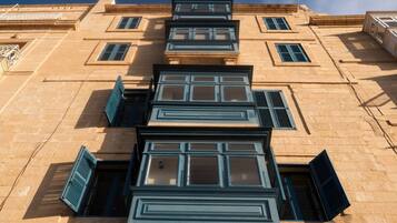 Un edificio de varios pisos con una serie de ventanas y contraventanas, algunas de las cuales están abiertas.
