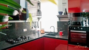 Une cuisine moderne avec des meubles rouges, un plan de travail noir et des appareils en acier inoxydable.