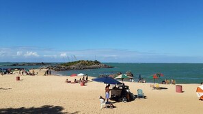 A beach with umbrellas, chairs, and people.