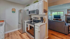 Una cocina compacta equipada con refrigerador, microondas, horno y encimera de granito.
