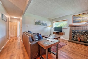 A living room with a sofa, a coffee table, a fireplace, and a television. - Riverfront family-friendly condo (Avon)
