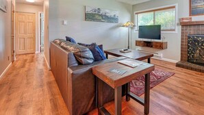 Una sala de estar con un sofá de cuero, una mesa de centro de madera, un televisor y una chimenea.