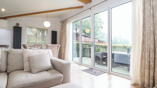 Un salón amplio con un gran ventanal corredera que da a un patio exterior.