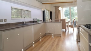 Una cocina moderna con una isla central, un área de comedor con mesa y sillas, y vistas al exterior a través de grandes ventanales.