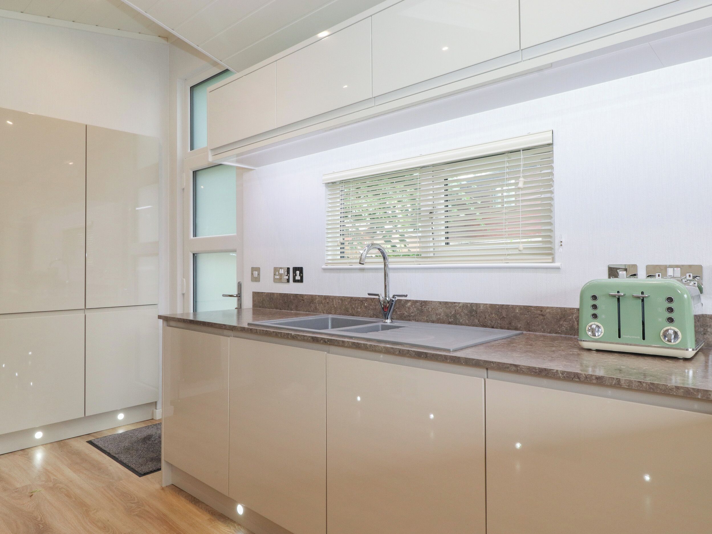 Una cocina moderna con un lavamanos integrado, una ventana con persianas y un tostador de estilo vintage sobre la encimera.