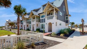 A modern multi-story residential building with a symmetrical facade, large windows, and a covered walkway.