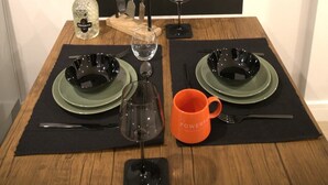 A dining table set with two plates, cutlery, a wine glass, a bottle of Prosecco, and an orange mug. A chalkboard in the background displays the text "Staged by @dcor_property_stagers". - Market Eden, King Deluxe suite (Northamptonshire)