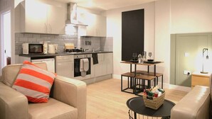A compact living space with a kitchenette, a dining area, and a seating area. - Market Eden, King Deluxe suite (Northamptonshire)