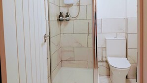 Un bagno con doccia, servizi igienici e uno scaffale con articoli da toilette.