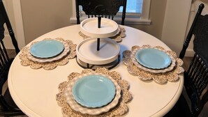 A dining table with two-tiered white stands, surrounded by black chairs. - Cozy Sunset Cottage on the family farm near Cave Run Lake and Morehead State  (Morehead)