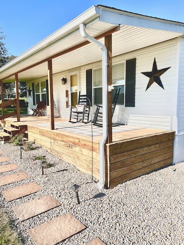 A house with a covered porch, wooden steps, and a star decoration on the wall.